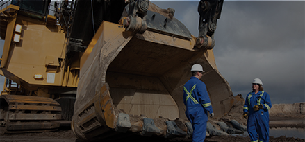 Two technical advisors dressed in blue in front of shovel