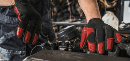 Gros plan sur des mains gantées rouges travaillant sur un moteur