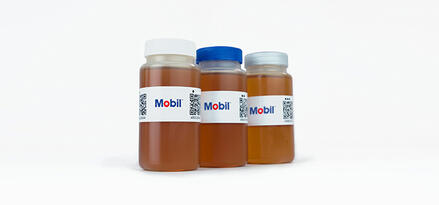 Three Mobil‑branded bottles filled with oil samples of varying colors, arranged against a white background