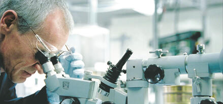 Man looking into a microscope in a lab