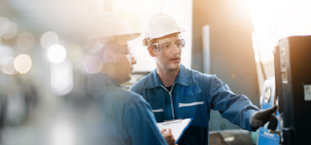 Two technicians in protective workwear discussing equipment inside an industrial facility