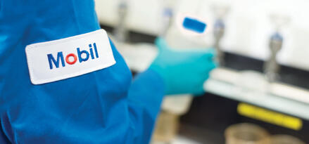 Mobil technician holding a bottle with the Mobil logo on his arm