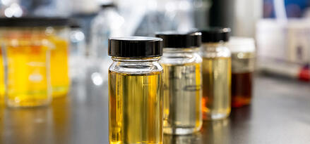 Several clear vials filled with oil samples of different colors arranged on a laboratory table.
