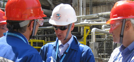 Industrial operators wearing protective equipment participating in a safety briefing at a processing facility